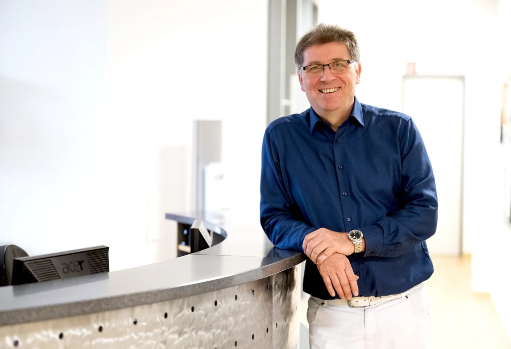 Dr. Andreas Meyer lehnt am Empfangstresen der Praxis